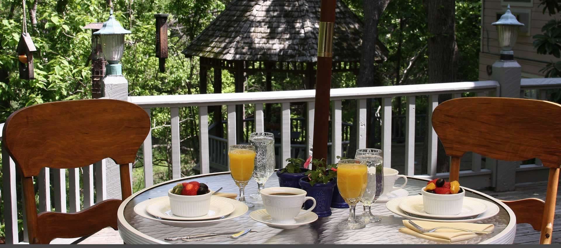 A breakfast table set on a porch with a gazebo in the background.